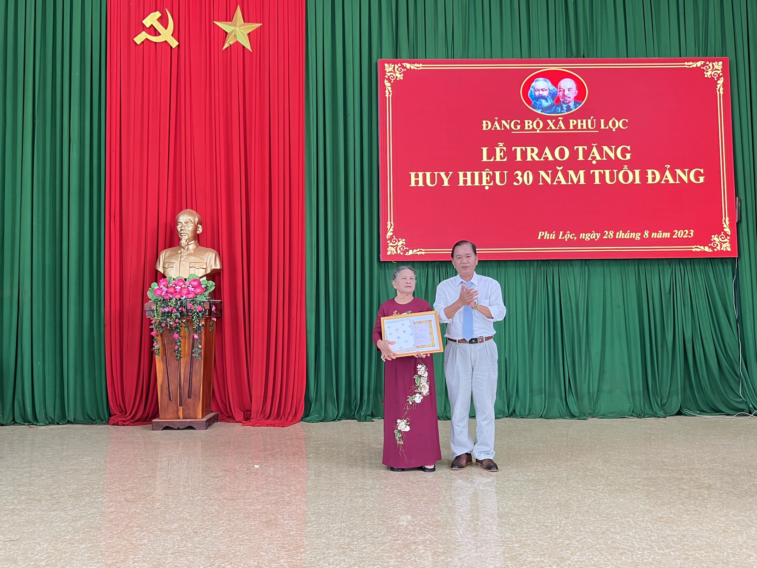 Đồng chí Lê Ngọc Ánh, Phó Bí thư Thường trực Đảng uỷ - Chủ tịch HĐND xã trao Huy hiệu 30 năm tuổi Đảng cho đảng viên Phạm Thị Hằng.